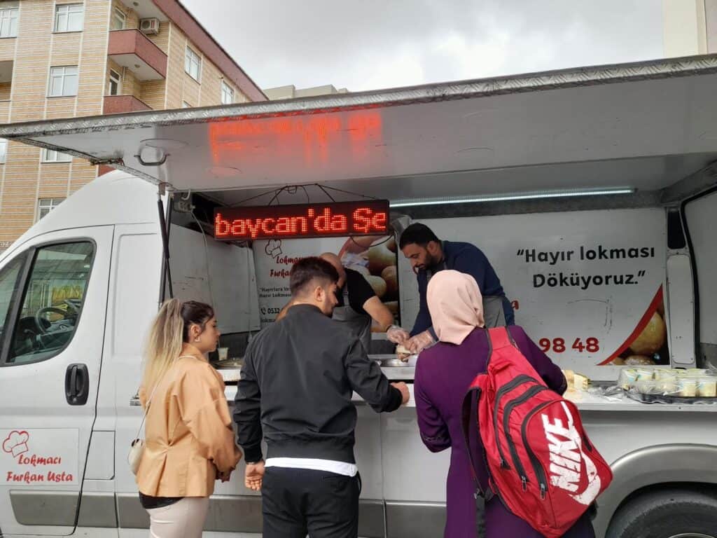 Lezzetli hayır lokması satış noktası, taze tatlı ikramı ve yardım çağrısı ile dikkat çekiyor.